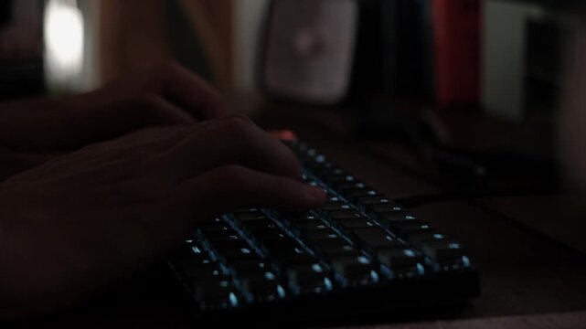 Close-up static shot of hands typing on a mechanical keyboard in a dim workplace setup indoors