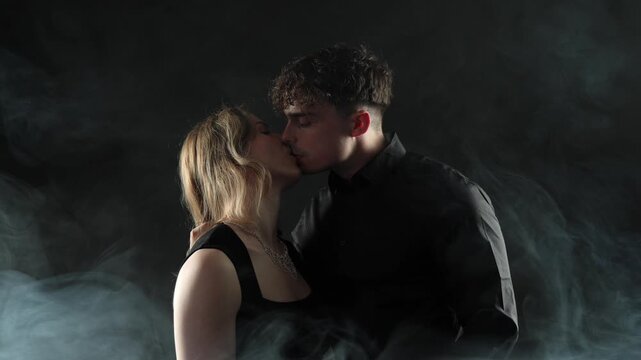 Romantic couple kissing in slow motion, enveloped by smoke against a dark background, conveying deep love and passion. This cinematic footage is projects related to relationships, Valentine s Day, ann