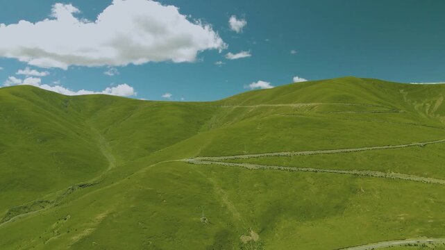 Green rolling hills under a blue sky with white clouds