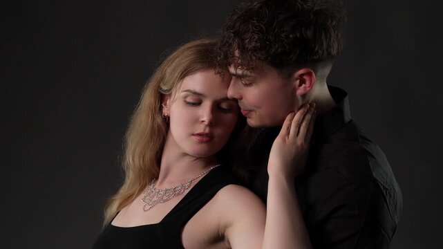An intimate couple embracing with tenderness and affection, highlighting their romantic connection and emotional bond. This studio portrait features a young man and woman in a close embrace against a 