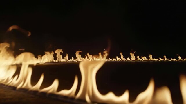 Igniting long line of fire flickering and spiking along burner in dark studio, low-angle camera