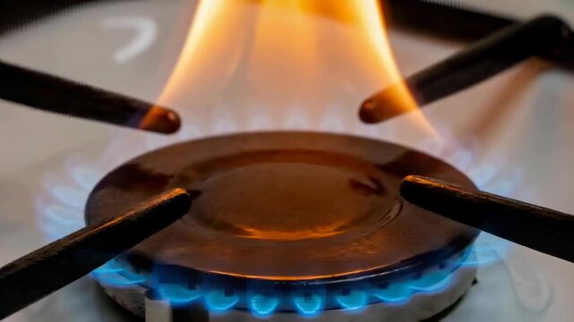 Flickering burner cap fueling orange flame column from steady blue base on white stove, with grates