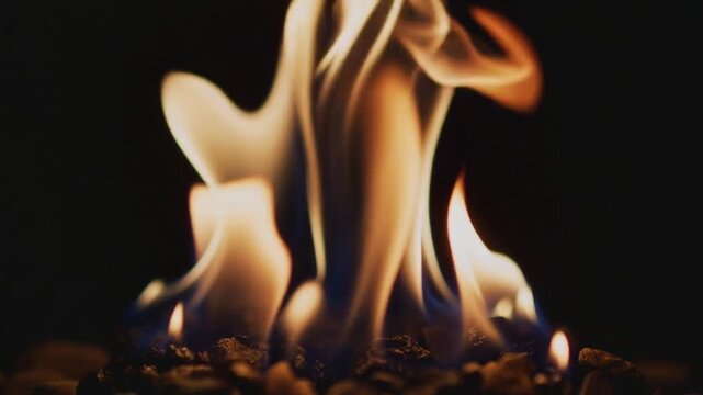 Dancing flame plumes rising and curling in studio close-up, with embers feeding combustion
