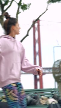 Teenage female wearing bright hoodie tossing glowing ball outdoors