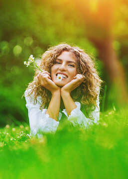 Pretty smiling authentic girl with camels flowers relaxing outdoor in summer by sunlight. Poster with copy space.