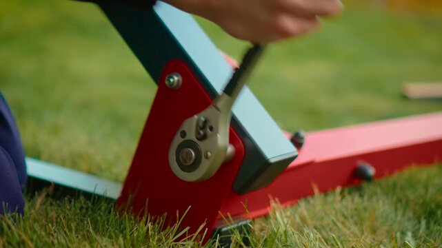Fast ratchet movement securing metal frame joint during outdoor build process. Motion blur tool action with red bracket, gray beam and worker hand. Home improvement maintenance concept with active