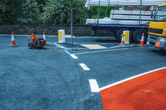 Construction work in urban area with equipment and vehicles during daytime near a parking lot