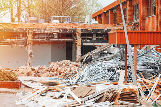 Construction site shows debris and materials after building demolition near a brick building