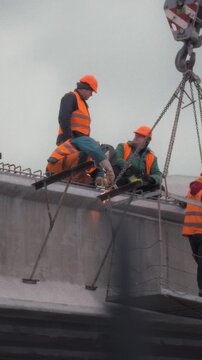 On a construction site, subcontractor crews in hard hats and safety vests repair a concrete bridge high above the river, securing the roadway and ensuring safe, functional travel for commuters