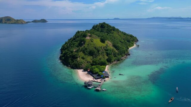 Komodo island showcasing a sandy beach, clear ocean, and a small jetty under blue sky. Nice aerial view fly push forward panorama drone