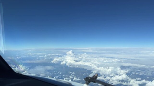 A pilot's perspective of fluffy clouds and a clear blue sky from the cockpit. Ideal for aviation themes or travel content.