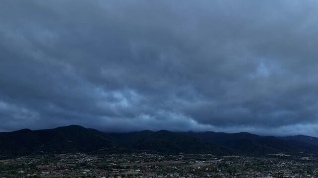 Aerial shot of dark clouds pouring toward the camera eventually exposing a beautiful ray of light in a timelapse