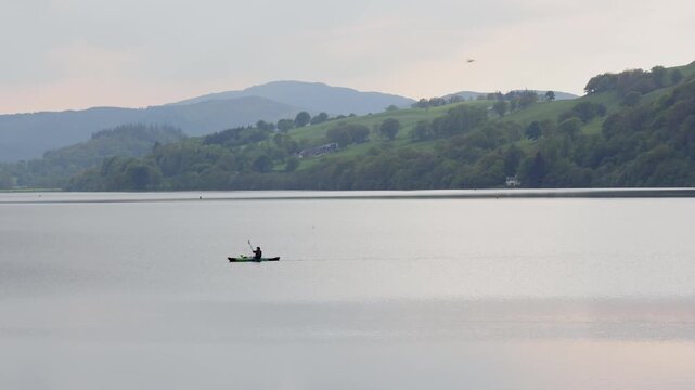 A canoe being paddled acrossLlyn Tegid or known as Bala Lake on a still Evening in Spring. This is the largest natural lake in Wales.. Gwynedd. UK