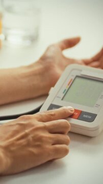 A young woman attentively checks her vitals with an electronic tonometer, reading the digital screen for blood pressure, showcasing how modern tech supports personal healthcare and medicine