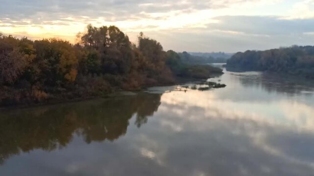 The meanders of a wide river flowing calmly through a forested plain at dawn on a cloudy autumn morning. The Inya River, Novosibirsk, Siberia, Russia.