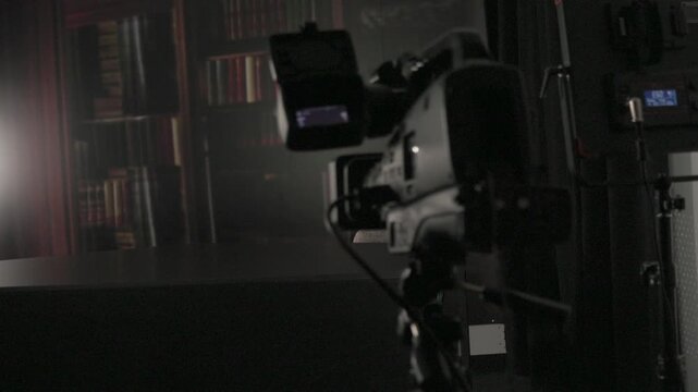Close-up of a videographer adjusting audio levels and settings on a professional video camera in a studio environment.