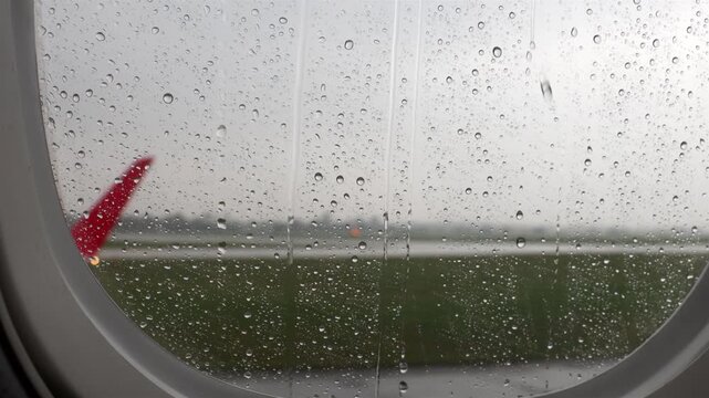 View from passenger window of airplane taxiing for takeoff in rain