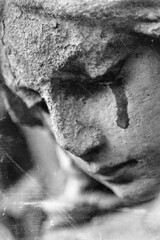 Fototapeta premium Crying stone angel with dark tear stain in emotional monochrome atmosphere