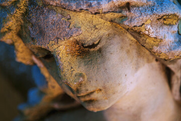Fototapeta premium Weathered angel statue with bowed head and warm dramatic lighting
