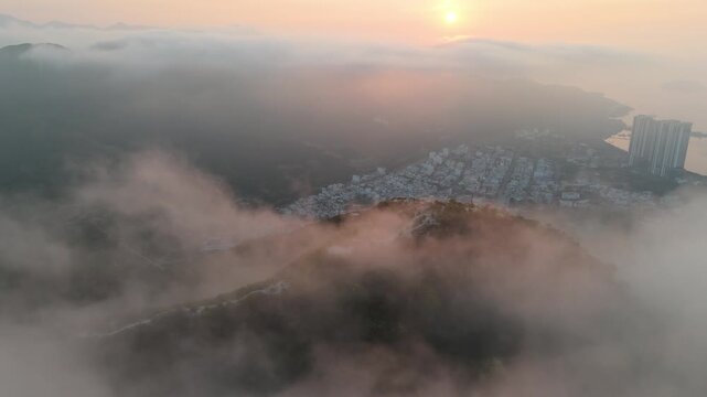 Hikers stand on a Cerro de la Popa mountain peak admiring the sprawling coastal city of Cartagena and calm Caribbean Sea as morning mist clears.