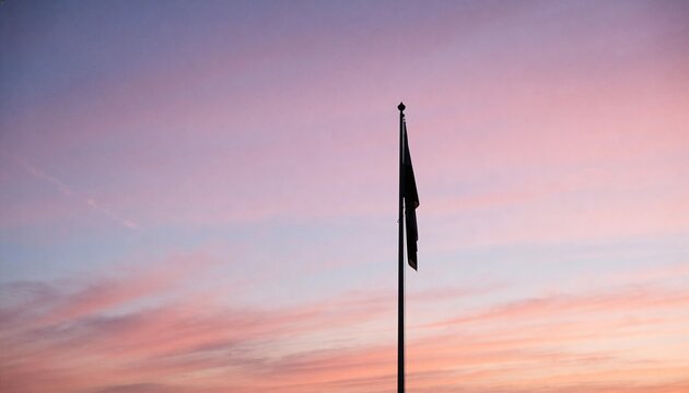 Standing tall metal flagpole displaying limp dark flags against pastel sunrise sky, ornate finial