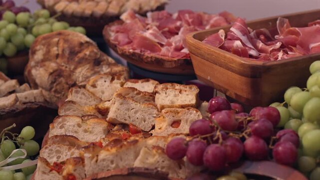 A large table of hams, cheeses and fruits at a wedding