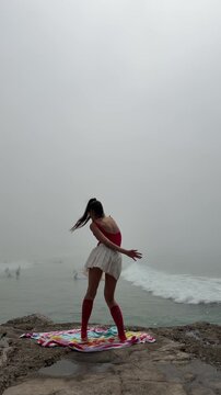 Seaside mist where woman dances amidst surf and weathered rocks