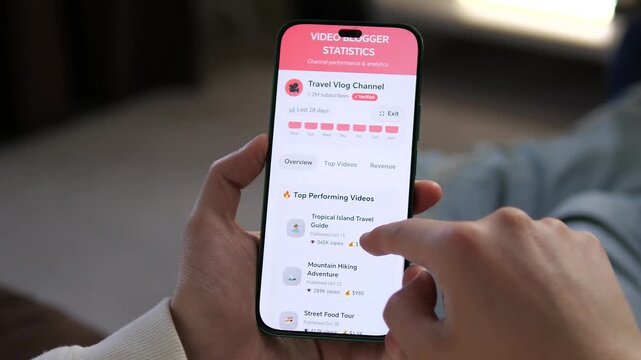 Track vlog success. Creator analyzes channel stats on a phone: views, income, and top videos. Perfect for marketing, social media business, and creator economy content. High-impact footage of digital