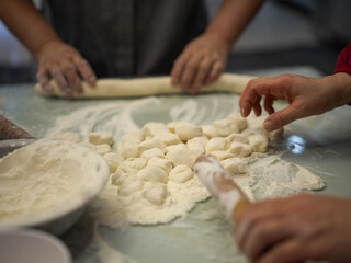 Fototapeta premium People Gather Around Cutting Board To Prepare Dough And Dumpling Wrappers