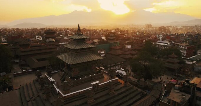 Detailed aerial view of an ornate multi-tiered Nepalese pagoda temple with intricate wooden roofs, glowing under warm sunset light in Kathmandu's Durbar Square.
