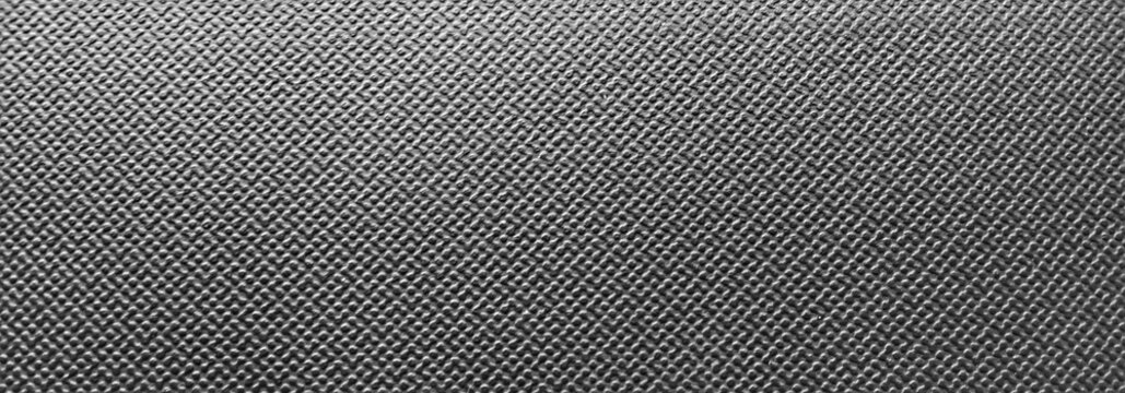 ​Black textured plastic surface background, dark synthetic leather pattern close-up