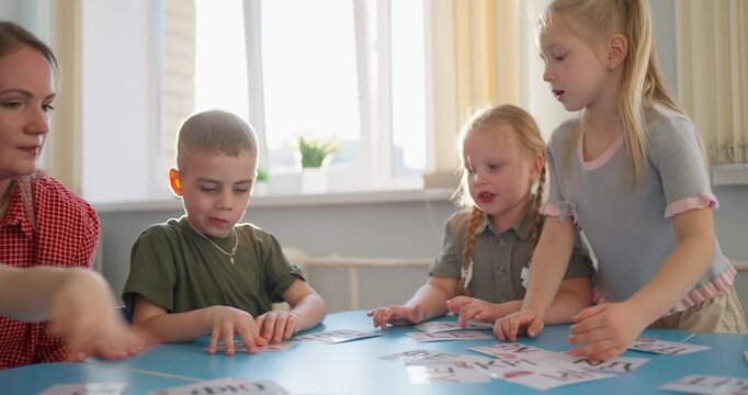 Teacher guiding young children through interactive card activities at a bright classroom table during an early learning group lesson