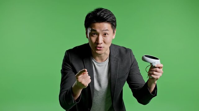 Asian man holding vr controller explaining technology against green screen background