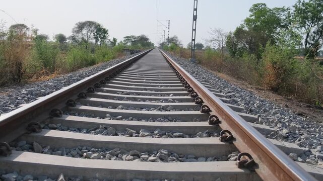 Horizontal eye-level shot of an empty railway track stretching into the distance with concrete sleepers and gravel ballast