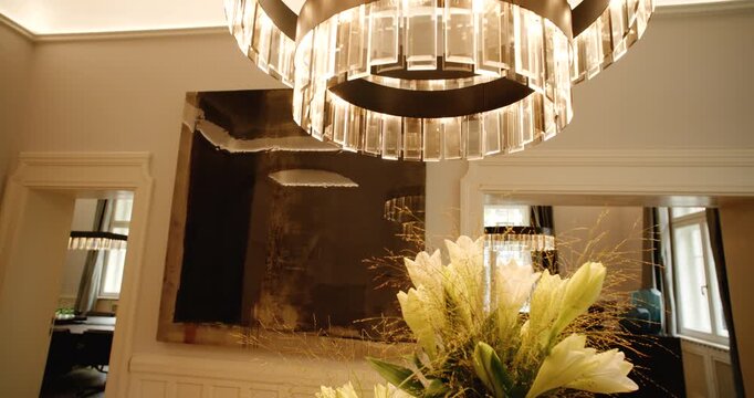 Tracking shot of interior room featuring crystal chandelier and white lily flowers in foreground