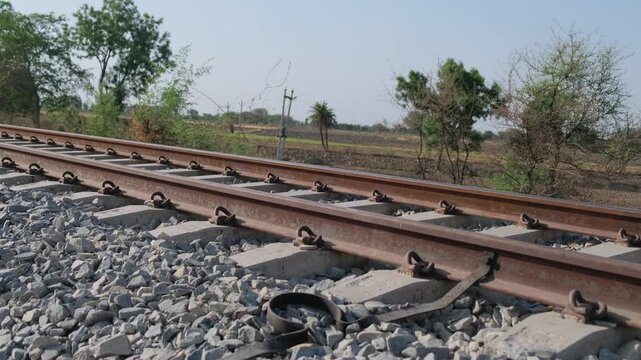 Horizontal eye-level view of a railway track with an overhead electrification mast in the distance