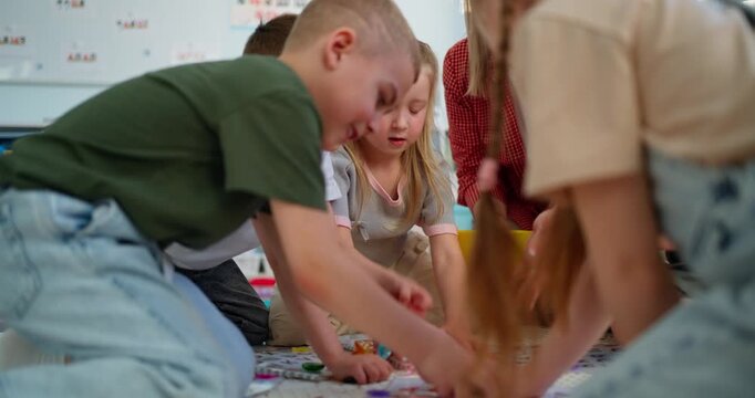 Teacher guiding young children during an interactive classroom floor activity, playing an educational matching game together in a bright preschool setting
