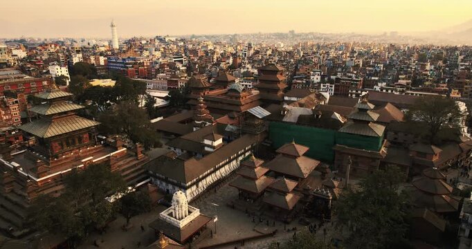 Aerial drone footage of Basantapur Durbar Square's temple complex with multiple pagoda spires, featuring the rebuilt Dharahara tower rising on the city skyline behind.
