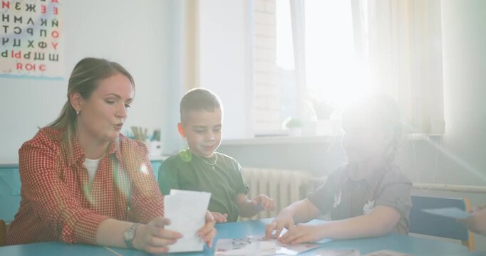 Teacher guiding young children through interactive card activities around a classroom table during an engaging early learning lesson