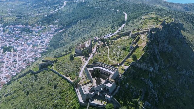 Cinematic 4K drone shot panning left from Palamidi Castle to reveal a breathtaking panorama of Nafplio city. Historic European architecture, red rooftops and coastal landscape in Greece.