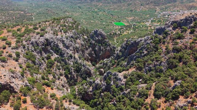 Aerial view of Kritsa Gorge featuring steep rocky cliffs and dry summer vegetation