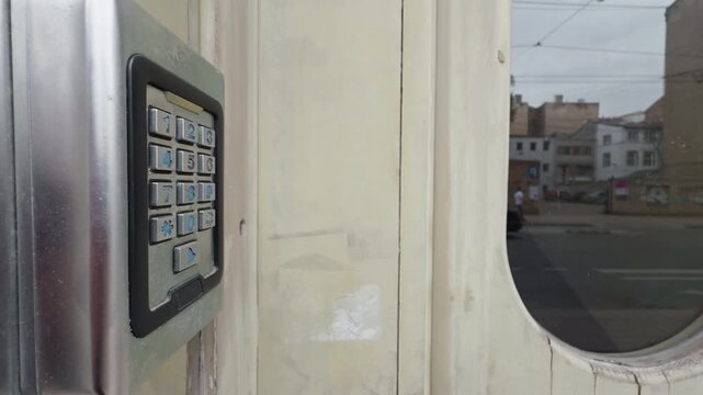 Detailed image capturing courier pressing buzzer on weathered building intercom in city setting
