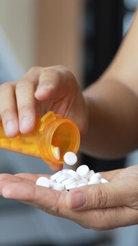 close up woman hand holding a medicine, with pours the pills out of the yellow orange medicine bottle. Stop drug use Taking Medication Caring for the health care medical concept.	
