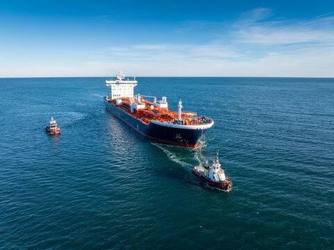 Large oil tanker ship escorted by two tugboats. Concept of maritime transport, global logistics, and international trade.