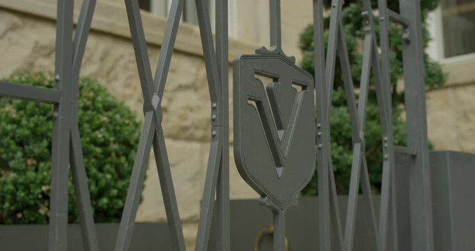 Close up view of a decorative metal shield emblem with the letter V on a gray security gate
