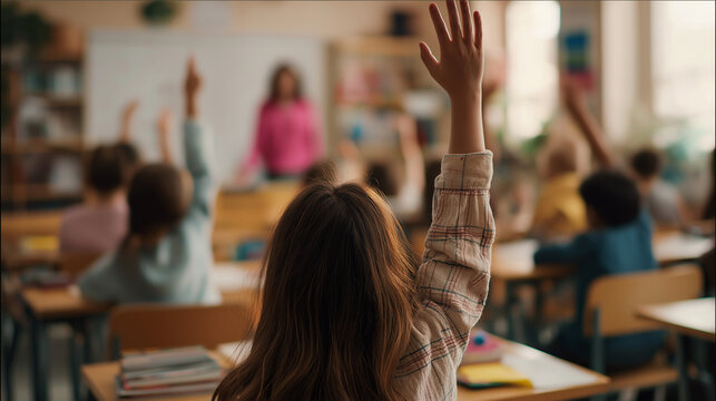 Students raising hands in a classroom, eager to answer teacher's question during a lesson