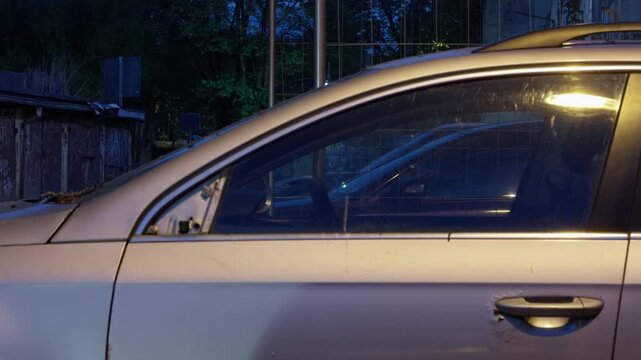 Quiet city street presents metallic sedan illuminated softly by streetlight with lens flare effects
