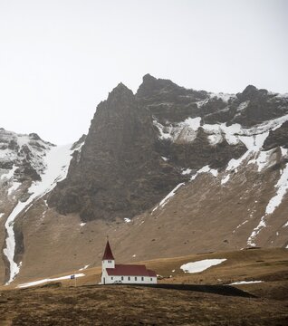 Red white church, V&iacute;kurkirkja in front of snow-covered mountains, V&iacute;k &iacute; M&yacute;rdal, south coast, Iceland