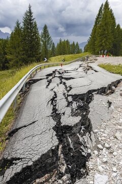 Broken road with cracks in the road surface, broken roadway of a mountain road, Belluno, Italy