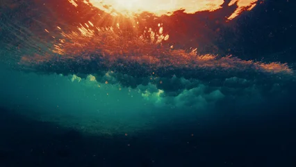 Underwater view of a breaking ocean wave with golden sunset light reflecting through the water surface and dynamic textures. © Dudarev Mikhail